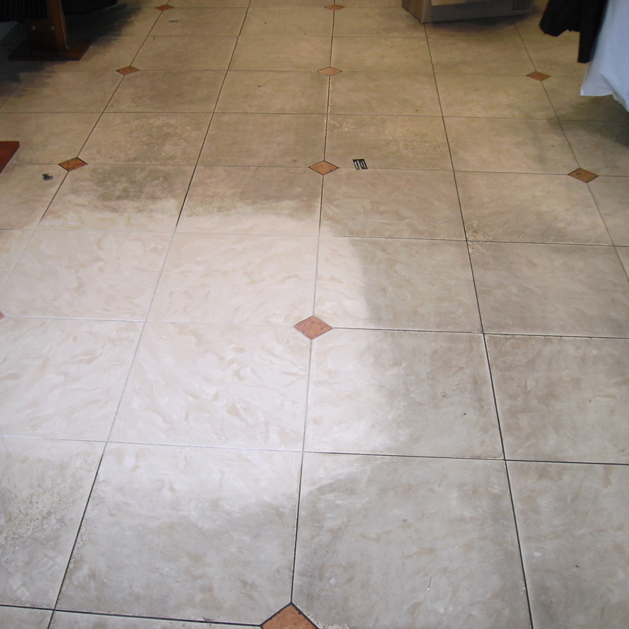 Stained tiles with a small area to the left that has been cleaned
